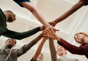 diverse group of people smiling and putting their hands together